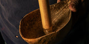 Close-up of a wooden bowl and rod being held.